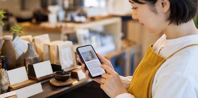 店舗でスマートフォンからSNS投稿を作成する日本人スタッフ
